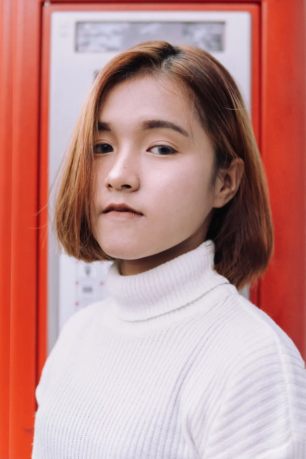 Close-up portrait of a young woman with bob haircut and natural look wearing a white turtleneck.