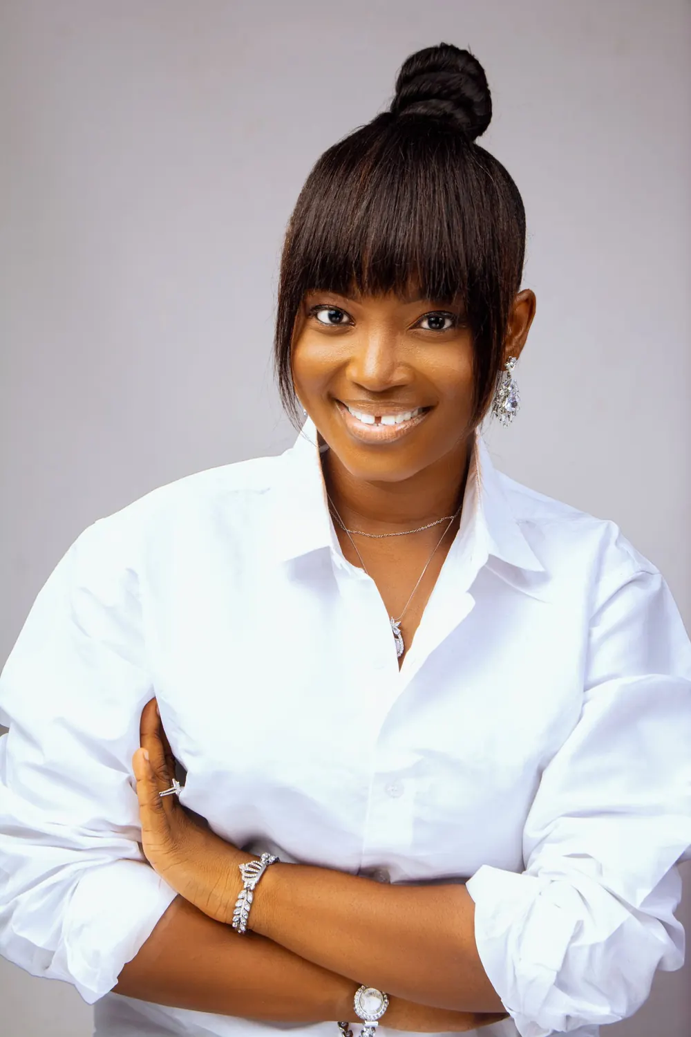 Smiling woman in a white shirt poses confidently against a neutral background.