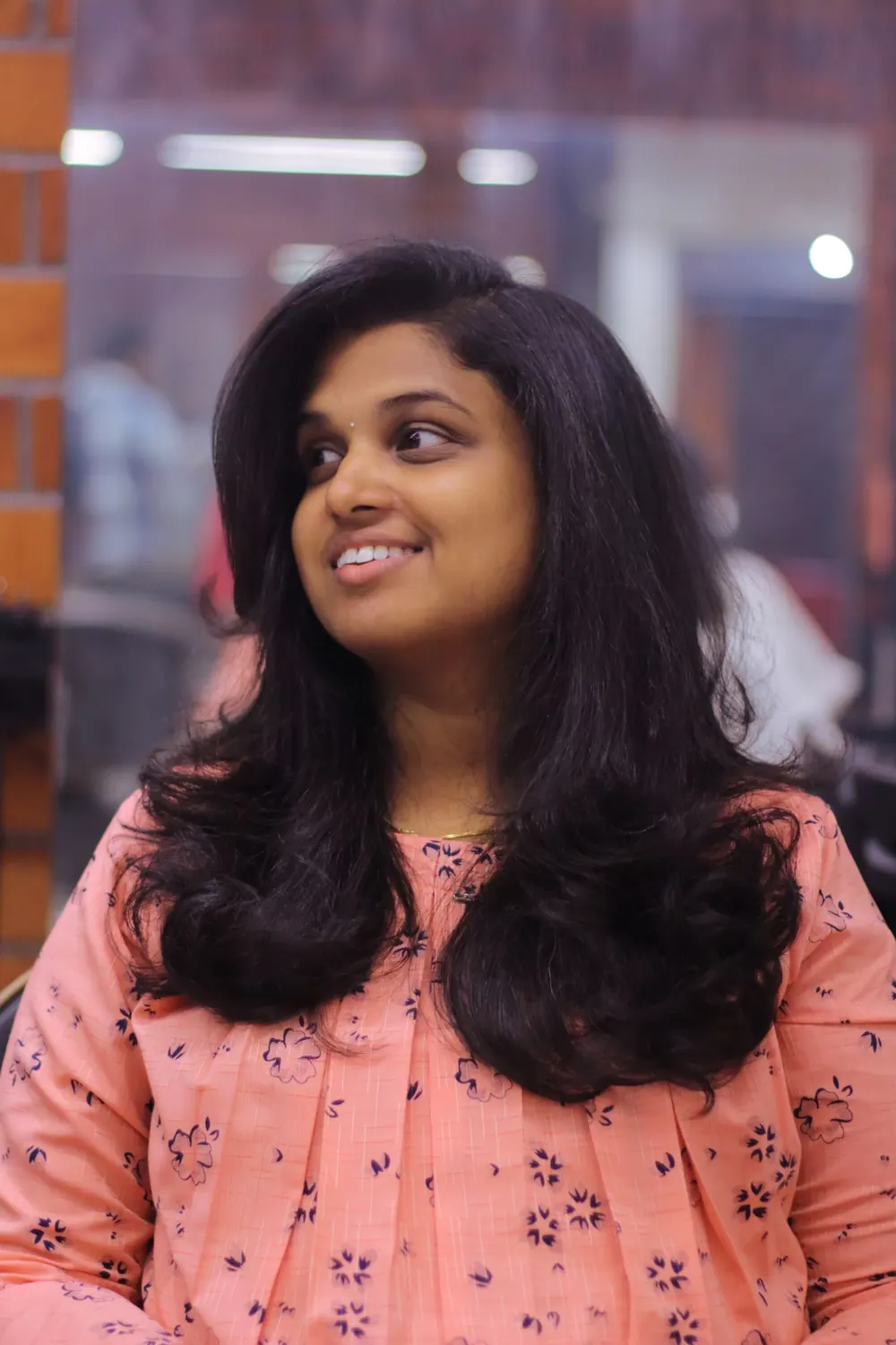Young woman with long brunette hair smiling at a hair salon. Relaxed and stylish atmosphere.